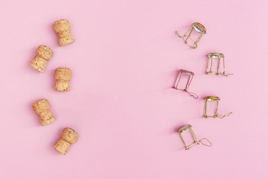 Corks and muselets from champagne sparkling wine on pink colored background with copy space. Christmas and Happy New Year concept. Flat lay.