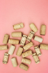 Used wine corks on pink paper background with copy space. Top view with wooden corks from bottle of wine. Flat lay.
