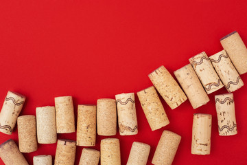 Assorted wine corks from white and red vine on red paper background with empty space for your text. Top view and flat lay.