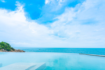 Beautiful outdoor infinity swimming pool in hotel resort with sea ocean view and white cloud blue sky