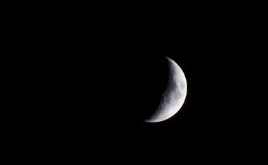 The moon in close-up. The moon against the black night sky. The moon is the main and only satellite of the earth that orbits the earth. Semi-lunar background. Beautiful half moon.
