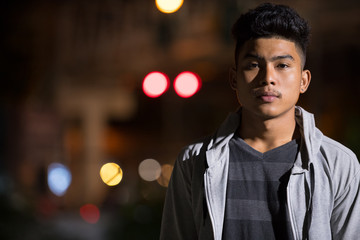 Face of young Asian man in the city streets at night