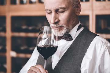 Sommelier Concept. Senior man standing holding glass smelling wine closed eyes joyful close-up - Powered by Adobe