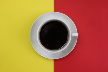 Obraz na płótnie Canvas a cup with a coffee stands on a red and yellow background at the same time