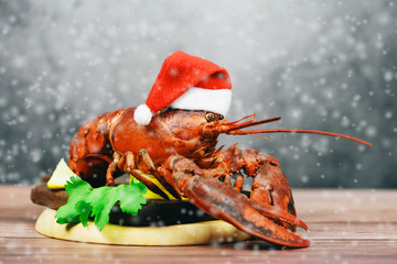 Fresh red lobster with christmas hat shellfish cooked in the seafood restaurant - Steamed lobster dinner food on wooden christmas table setting with snow celebrate in holiday winter festive