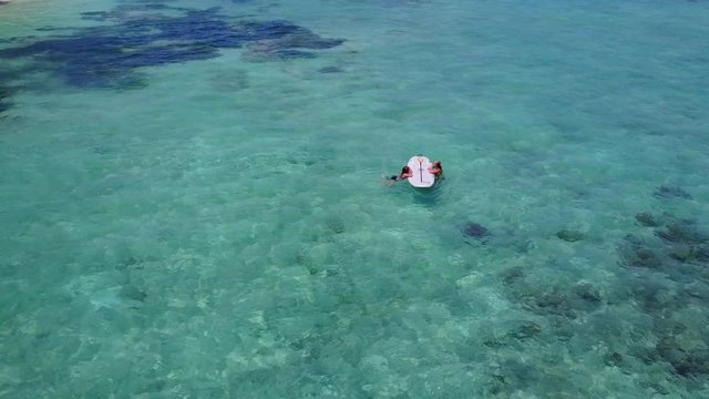 Couple resting on surfboard talking to each other about holidays in Barbados, emerald shallow waters