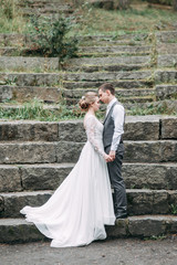 Wedding in the European style in nature. A bride in a white dress on a stone staircase.