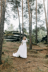 Elegant ceremony in European style. Beautiful bride in white flying dress in the forest.