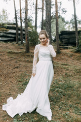 Fototapeta premium Elegant ceremony in European style. Beautiful bride in white flying dress in the forest.