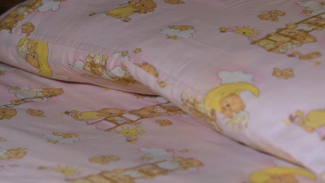 The hands of the baby girl put a case-the mouse under the pillow for the tooth fairy. Girl sitting on the bed and preparing to sleep. Shows the tooth box to the camera. Close up