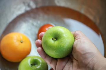 hand holding green apple cleaning in kitchen 