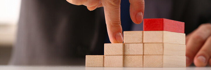 Male hand holds red wood block of stair