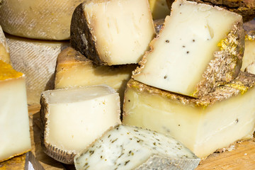 Large selection of cheese varieties on a wooden table background.