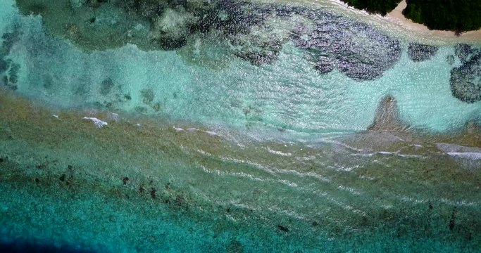Wonderful texture with colorful sea bed full of coral reefs and underwater rocks splashing by white waves in Cook islands