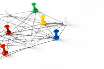 Network with colorful pins and string,  linked together with string on a white background suggesting a network of connections.