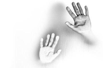 Woman's hands behind a glass wall, where she is  shouting for help