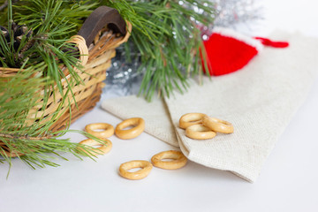 Obraz na płótnie Canvas small edible rings scattered on a table on a white background with green spruce branches, a wicker basket, a linen napkin, New Year's decor