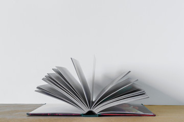 Opened book over brown table at white background