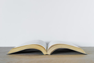 Opened book over brown table at white background