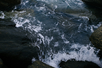 Sea waves crashing into the black rocks, Ocean wave texture background.