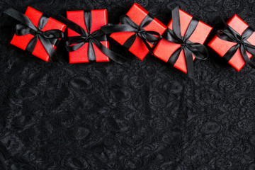 Red gift boxes with black ribbons on a black lace background. Holiday or black friday concept.