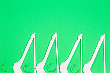 White wooden hangers arranged on pastel green background. Shopping, sale, promo, social media, new season concept