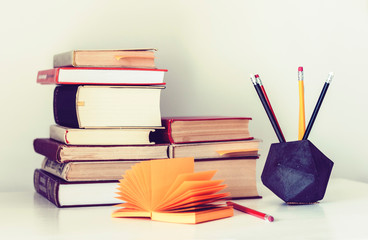 Stack of books and pencils in holder, education concept background, many books piles with copy space for text.