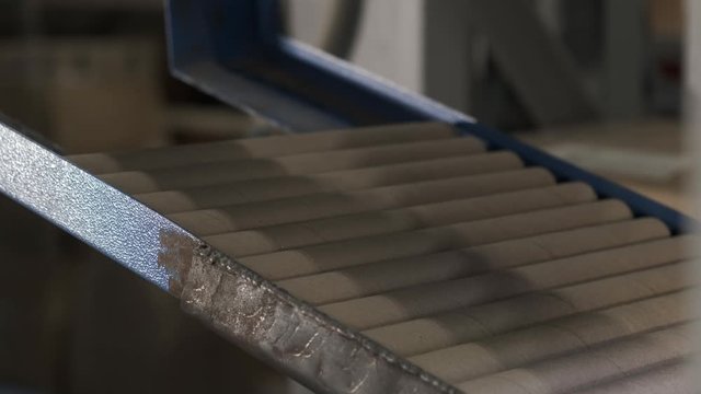 Close-up shot of a part of the machine with a mechanism for feeding cardboard blanks to the conveyor, an outdated machine in an outdated production, cardboard tubes, a person puts new tubes in a queue