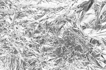 Soft light crumpled silver foil background with cracks, wrinkles, random tracks.