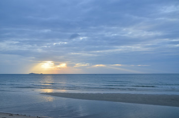 A picturesque tropical yellow coloured cloudy coastal sunrise seascape in a steel blue sky. Thailand.