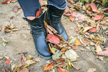 Women's boots on fallen autumn leaves.