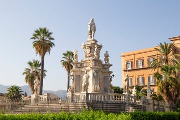 Fototapeta na wymiar Palermo, Italy, September 19, 2019: A house with a classic statue next door and palm trees outside the street on a sunny day in Palermo. 
