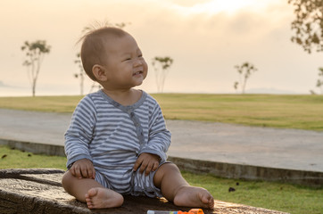 happy cute asian baby sit and smiling with  sunset light outdoor