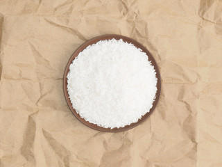 Spices help maintain good health and improve appetite, top view on craft paper background. Coconut flakes in clay plate. Modern apothecary, naturopathy and ayurveda concept.