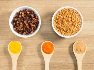 Cloves, fenugreek, turmeric, masala, chili pepper on brown wooden background. Indian cuisine, ayurveda, naturopathy, modern apothecary concept