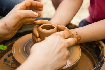 A close up view on ceramic production process on potter's wheel with children. Clay crafts with kids concept.