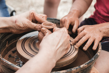 A close up view on ceramic production process on potter's wheel with children. Clay crafts with kids concept.