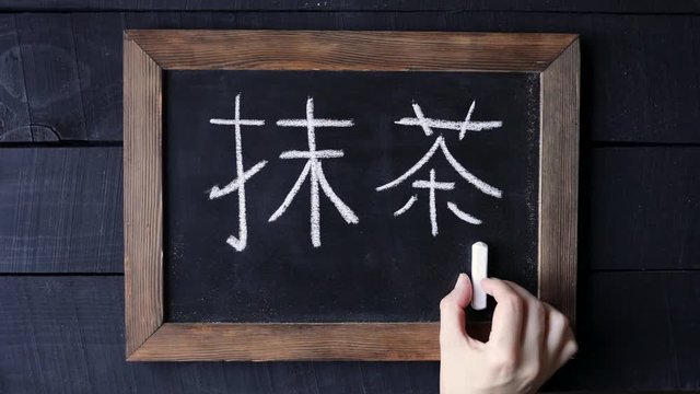 Woman write japanese symbols at blackboard