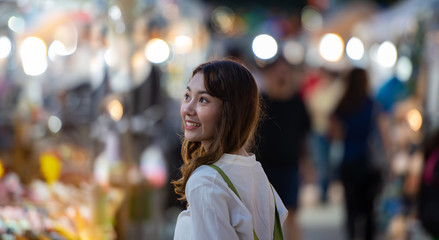 Travel young woman in night street market with bokeh background.