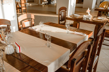 Glasses, flower fork, knife served for dinner in restaurant with cozy interior