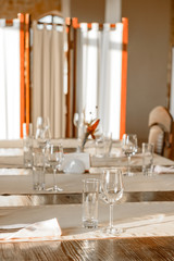 Glasses, flower fork, knife served for dinner in restaurant with cozy interior