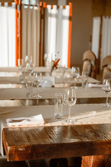 Glasses, flower fork, knife served for dinner in restaurant with cozy interior