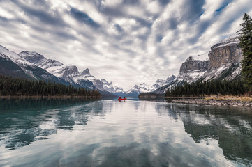 Traveler canoeing on Maligne lake with altocumulus clouds in Jasper