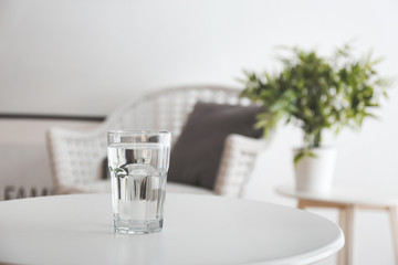 Glass of fresh water on table in room