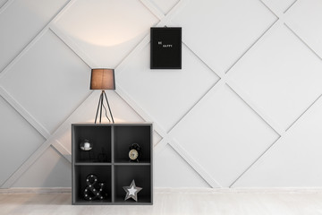 Stylish shelves with lamp near grey wall