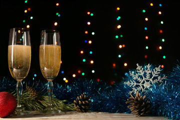 The concept of celebrating the New Year and Christmas. Dinner of a couple with two glasses of champagne. Copy space for text on black background with blurred lights.