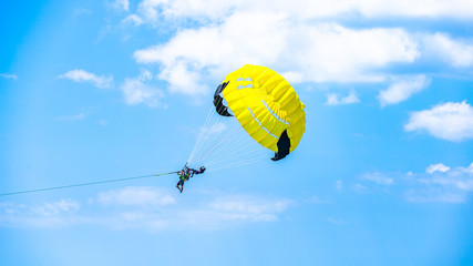 Happy couple Parasailing on Tropical Beach in summer, Tropical Paradis, With a parachute for parasailing a couple flies through the air with blue sky in the background.