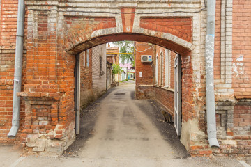 Fototapeta na wymiar Brick arch the courtyard in the Russian city