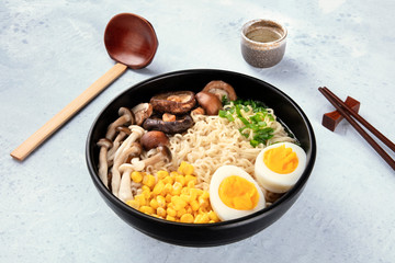 Ramen. Soba noodles with boiled eggs, mushrooms, and vegetables, with sake, traditional wooden spoon, and chopsticks