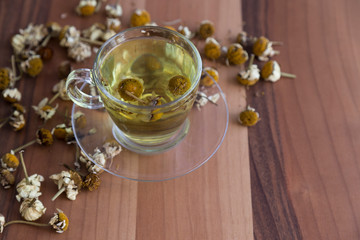 the cup of daisy tea on the wooden background.